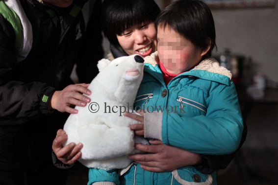 Nun Tian Wenjiao 田稳姣 holds Lin Xiaoxue 林晓雪 as she is give a cuddly bear bought by the charity PTE. HIV in China.